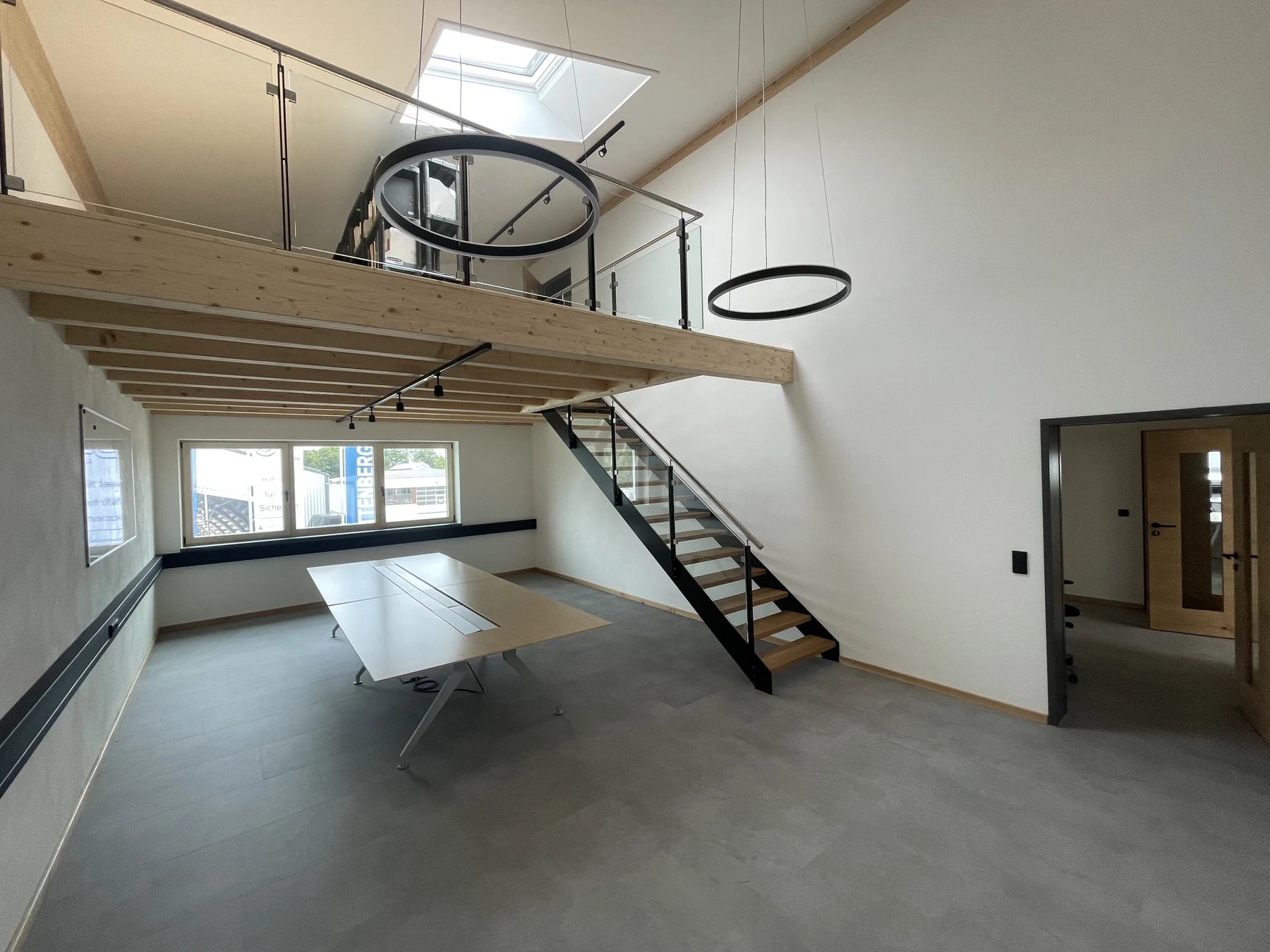 Besprechungsraum mit offener Holzgalerie, Stahltreppe und Ringleuchten im Gewerbeensemble Attenberger in Passau