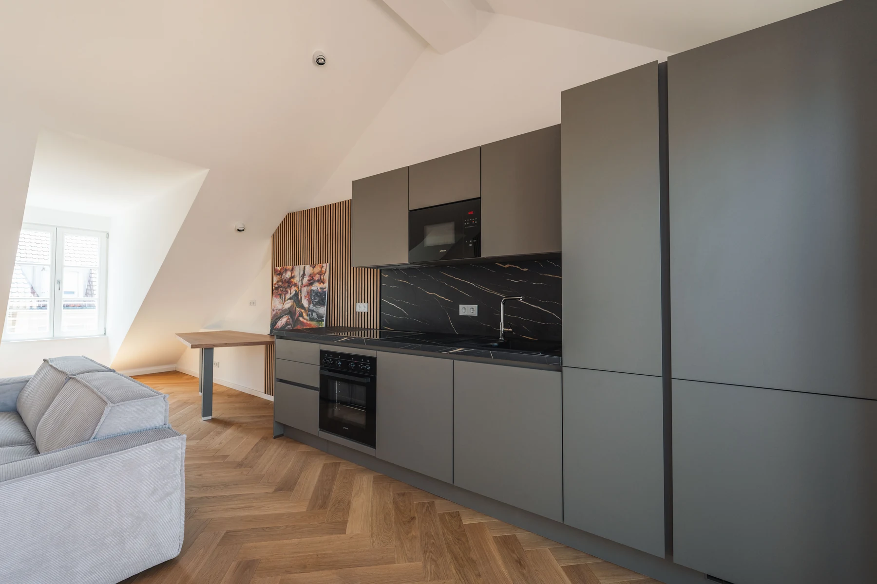 Seitliche Ansicht der Küche mit dunklen Fronten und schwarzer Arbeitsplatte – Schellingstraße 32, München-Schwabing