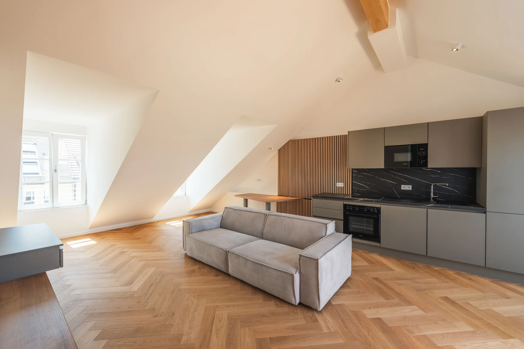 Sofa vor der offenen Küche unter Dachschrägen und sichtbarem Holzbalken – Schellingstraße 32, München-Schwabing